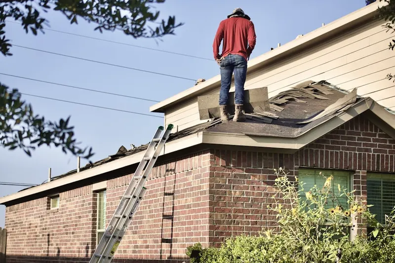 Professional roofer working on a residential roof in Raymore